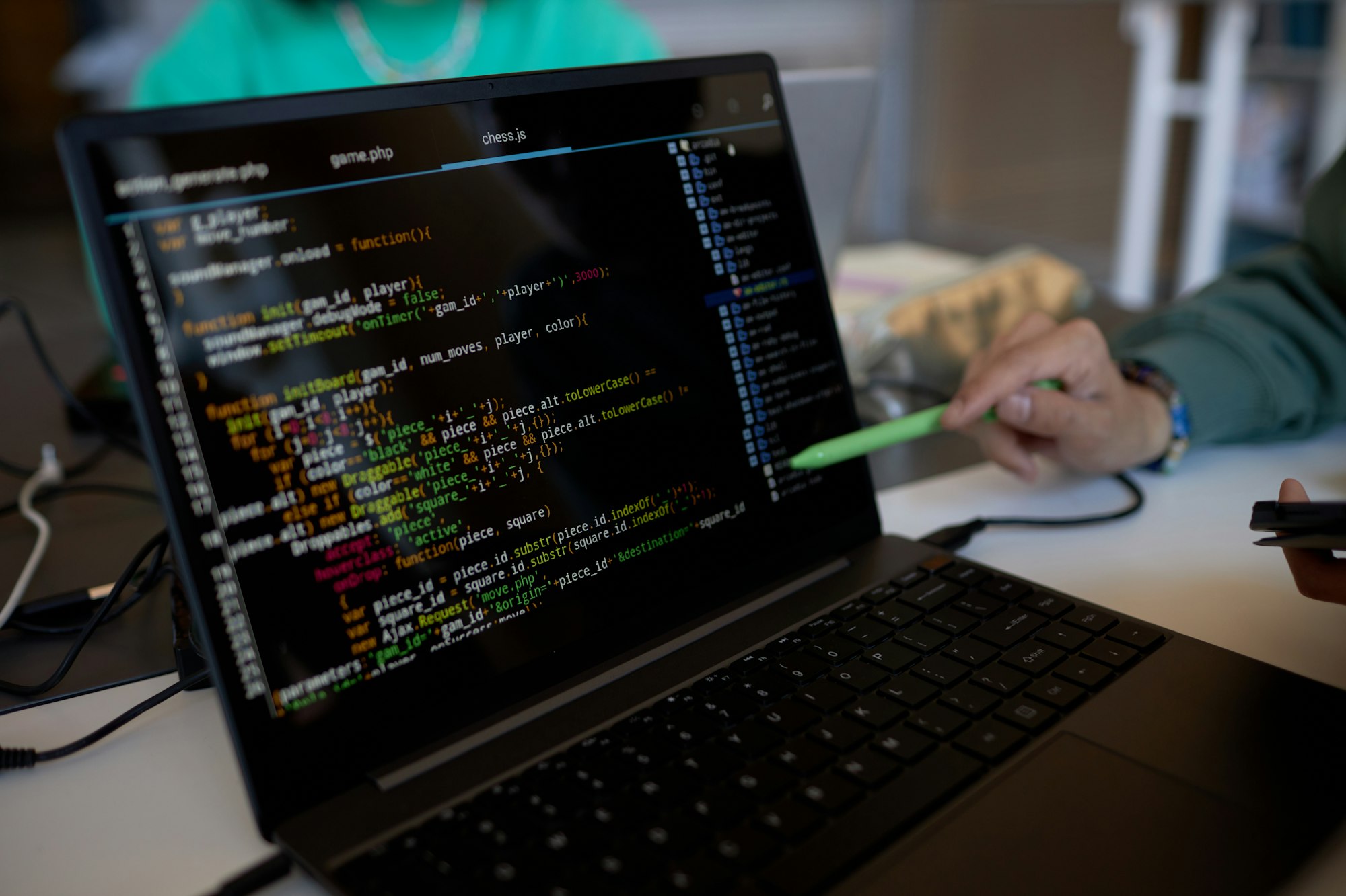 Focus on laptop screen with coded data and pen held by hand of young man